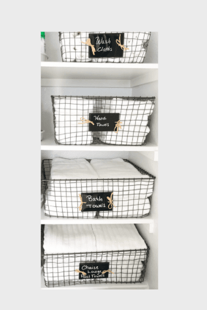 Wire baskets holding bright white linens in a neatly organized linen closet