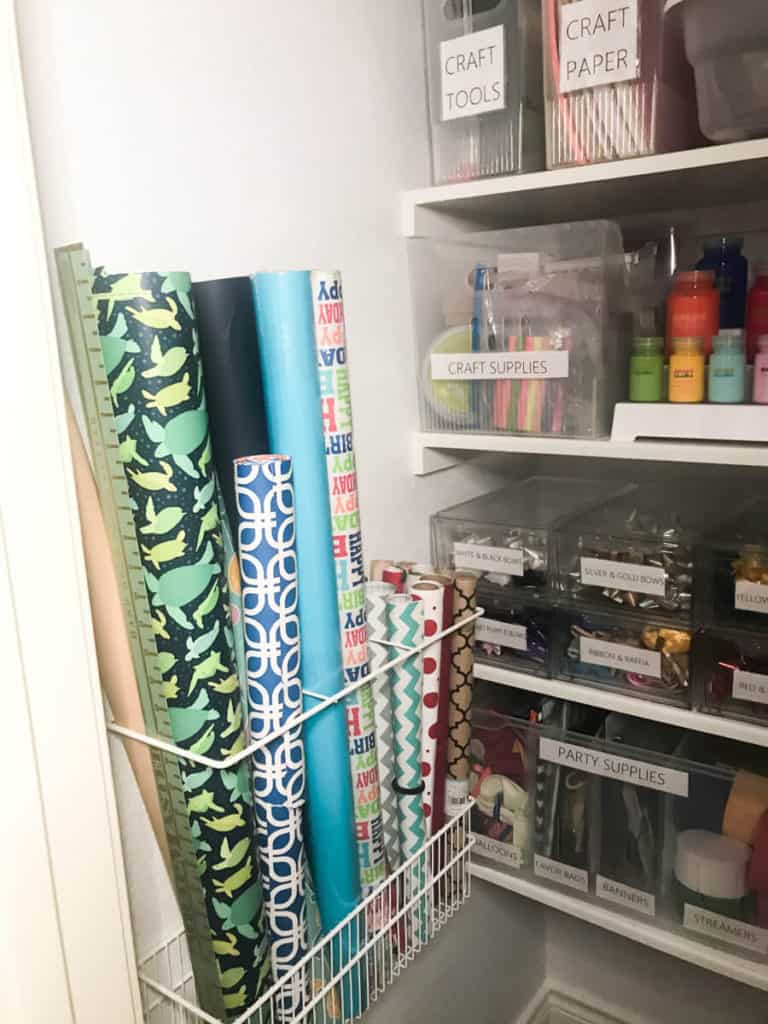 Elfa wall rack holding different styles of wrapping papers in a closet used for organizing craft supplies