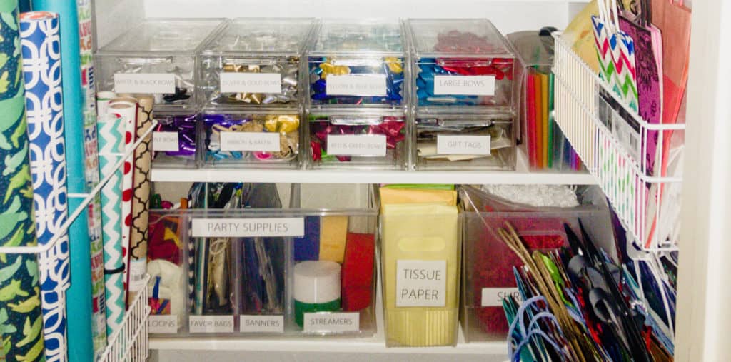 Neatly organized craft and gift closet with wrapping paper, bows, party supplies, and crafts