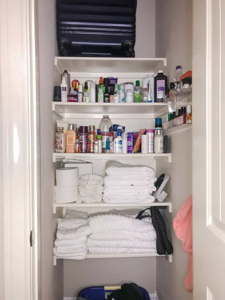 A disorganized linen closet filled with towels and hair and beauty products