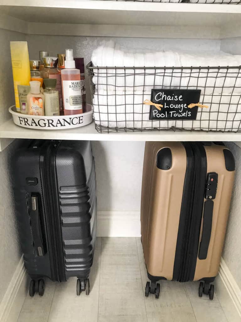 luggage under neatly linen closet shelves in a neatly organized linen closet
