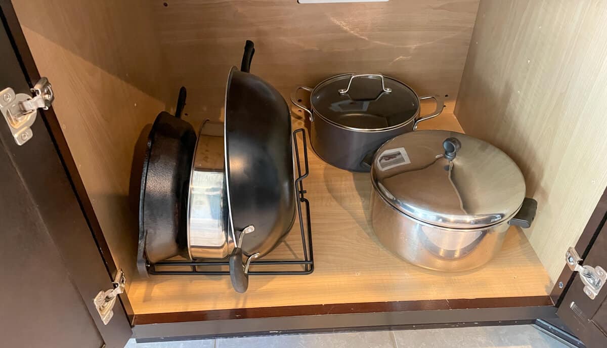 An organized kitchen cabinet housing pots and pans