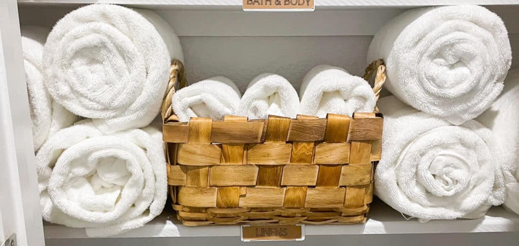A shelf in a bathroom storage closet filled with fresh white linens