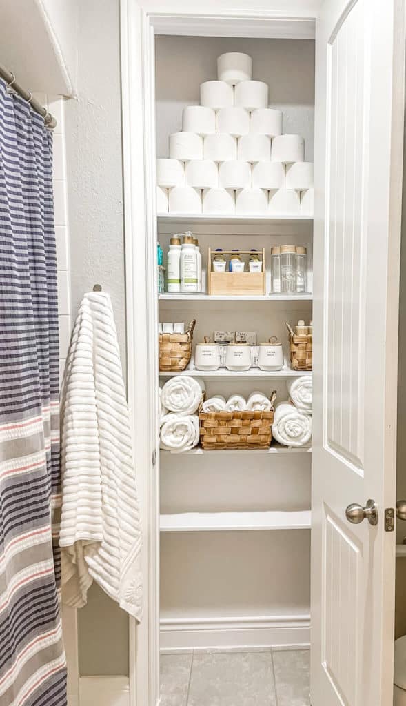 A bathroom storage closet organized with bath items and linens