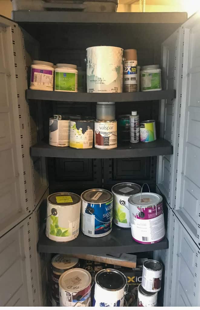 A messy garage cabinet filled with paint cans
