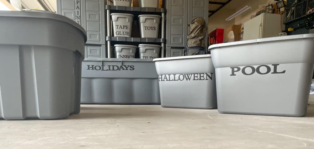 Gray, labeled storage bins on a garage floor