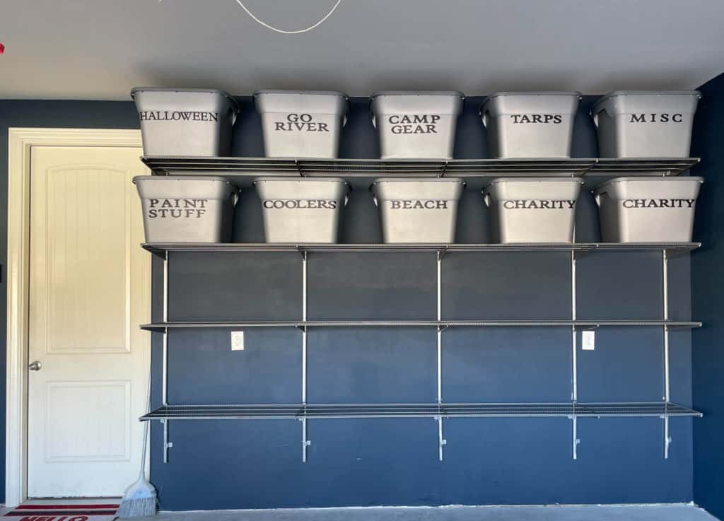 A garage shelving unit with storage bins on two of the shelves
